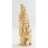 A Japanese ivory tusk carving, Meiji period, 1868-1912, as a robed bearded elder holding a chick,