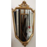 An Empire design gilt framed wall looking glass of heraldic shield form