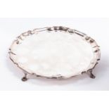 An Edwardian silver salver, pie crust rim on four stepped hoof feet,