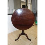 A George III mahogany tilt-top tripod table, the circular top supported on a birdcage mechanism,