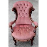 A Victorian mahogany deep buttoned armchair, carved ear pieces,