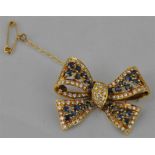 An 18ct. gold, sapphire and diamond brooch, in the form of a tied bow, each section of "ribbon"