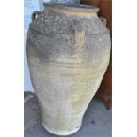 A large weathered terracotta triple handled amphora pot, with reeded body, 98cm high.