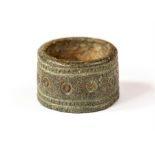 A bronze ring with wide band decorated with border of beading, ring-and-dot motif to the centre.