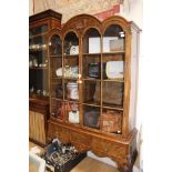 A George I style burr walnut glazed cabinet on stand, arch moulded,