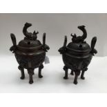 A pair of Oriental bronze censors, relief moulded with Dragons,