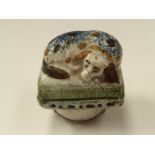 An 18th Century Delft Prattware snuff box, modelled as a Spaniel on cushion,