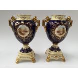 A pair of Coalport twin handled pedestal vases, hand painted cameo, cobalt ground,