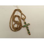 An 18k yellow gold textured crucifix pendant set seven various square cut emeralds;