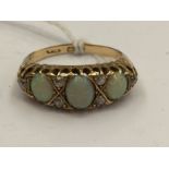 An 18ct gold ring set with three oval opals, with diamond accents, scroll shoulders, ring size M,