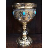 A gilt metal goblet with etched foliate scroll design set with turquise stones,