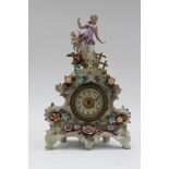 A French style mantle clock, being encrusted with flowers and having woman and child as the finial,