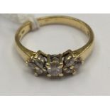 A gold ring (indistinct stamp) set with a square diamond and six diamond chips in the form of a bow,