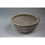 A ceramic grey ware bowl with rolled rim and body rounding to the base ring. Base with inked