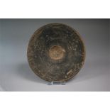 A black glazed pottery dish with a gently sloping floor and overhanging rim and a concave tondo, the