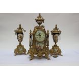 A gilt metal mantle clock with garniture, transfer printed decoration to ceramic inserts,