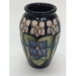 A Moorcroft blue ground miniature vase, decorated with tube lined stylized violets,