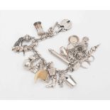 A silver charm bracelet with various charms including Victorian tassle propelling pencil,