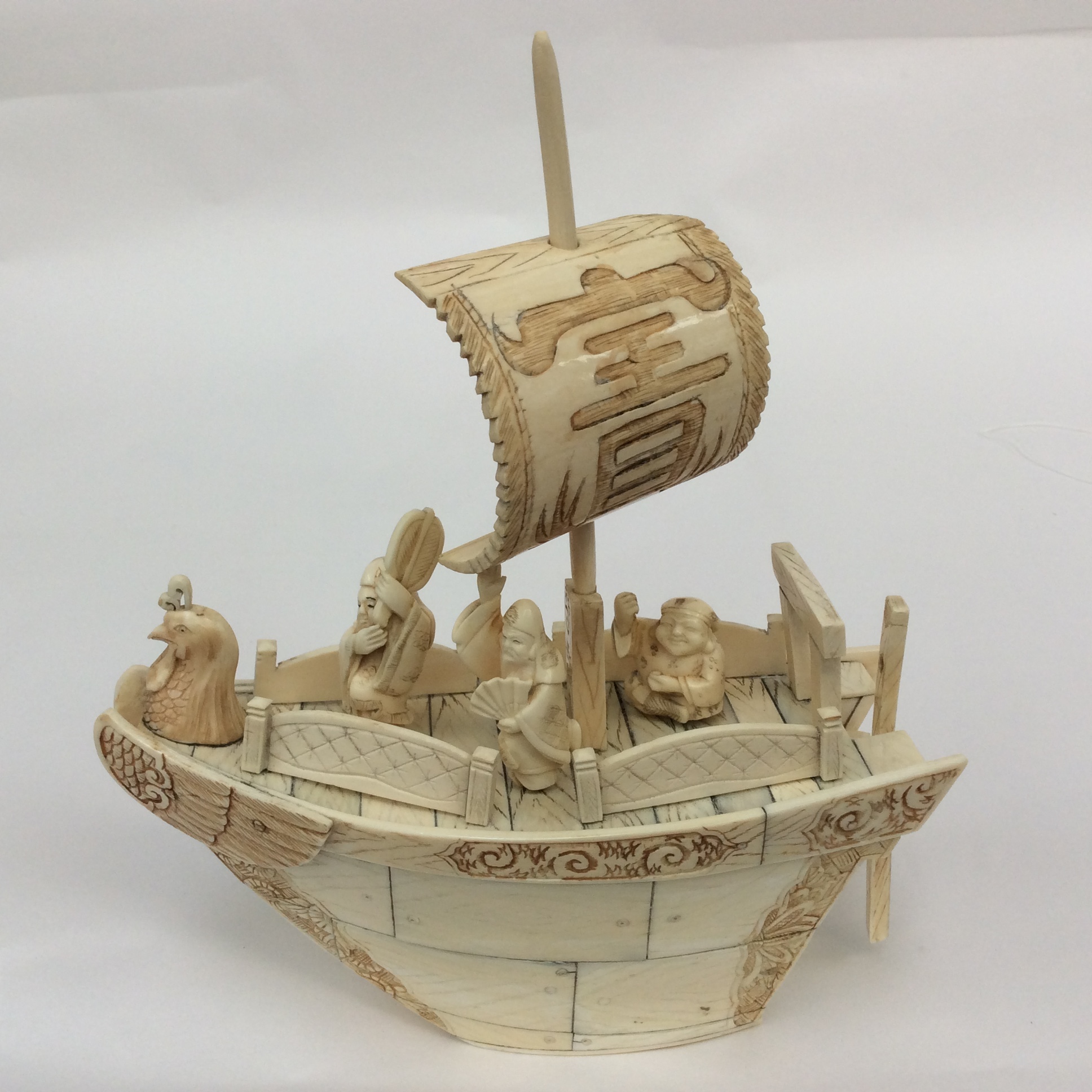 An early 20th century Chinese carved ivory junk boat with three male figures with cockeral head