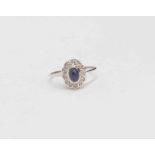 A Sapphire and diamond ring comprising oval cabochon sapphire, diamond surround in 14ct white gold,