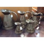 Five graduated copper jugs,