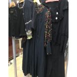 A black silk 1930s large dress with floral sleeves, smocked detail on waist, a black crepe dress,