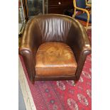 An early 20th Century brown leather tub chair