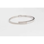 A diamond and 9ct gold bangle, hinged crossover hollow design,