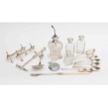 Four silver topped glass bottles; seven silver spoons; silver spoon; plated knife rests;