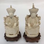 A pair of ivory carved male of female seated figures on stands