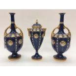 A pair of Royal Worcester pedestal narrow necked vases with twin gilt handles,