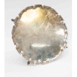 An Art Deco period silver salver, with shaped edge and raised on four feet, London, 1932,