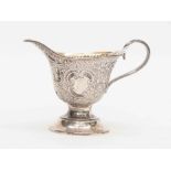 A late Victorain parcel-gilt cream jug, helmet shaped profusely chased with scrolling foliage,