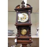 An eight day walnut cased wall clock, having a white enamelled dial, turned gallery,