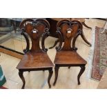 A pair of mid Victorian oak hall chairs, with cartouche shaped backs and solid seats,