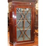 A George III mahogany hanging corner cabinet fitted with a single glazed door enclosing three