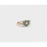 An emerald and diamond cluster ring, comprising a flower head emerald detail,
