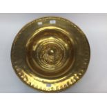 A brass alms dish, inscription translates to 'One hand washes the other'.