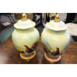 Game interest - a pair of Coalport Richard Budd painted vases and covers, of baluster outline,