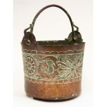 An Arts and crafts copper coal bucket, of circular form, embossed with dragons, hunting weaponry,