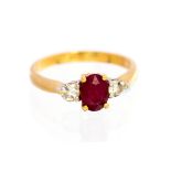 A ruby and diamond three stone ring, the central oval faceted ruby approx 7mm x 5mm,