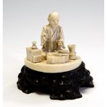 A Japanese ivory okimono of a craftsman, Meiji period, 1868-1912, on a wooden plinth,