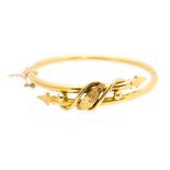 A 9ct gold hinged bangle with spear head terminals, foliate engraved centre panel,