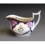 A Newhall London shaped cream jug decorated with pink flowers within a blue ground and gilding,