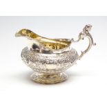 A George IV melon shaped silver milk jug, the body profusely chased with flowers and foliage,