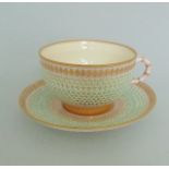 A Royal Worcester Reticulated tea cup and saucer, picked out in pink blue turquoise and gilt,