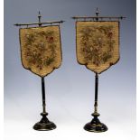A pair of Victorian table top pole screens, silk backed woolwork panels,