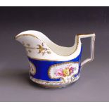 An English porcelain creamer, blue ground, decorated with flowers within gilt cartouches,