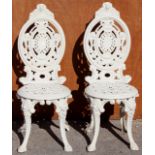 A pair of Victorian style cast iron white garden chairs, each approx 94cm high,