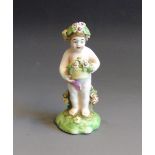 A Derby cherub holding a basket of flowers, standing on a green base, circa 1780-1800, 11.